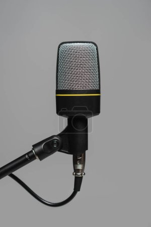 Vista de cerca del micrófono con cable negro en soporte de metal aislado en gris, foto de estudio 