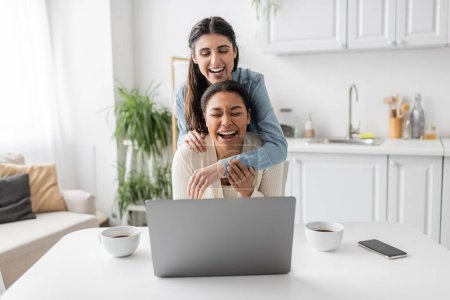 happy engaged lesbian couple showing engagement ring during video call at home 