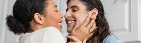 overjoyed multiracial woman with engagement ring on finger hugging girlfriend, banner 