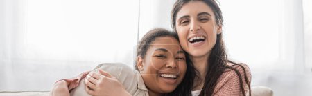 Téléchargez les photos : Femme lesbienne enchantée embrassant petite amie multiraciale dans le salon, bannière - en image libre de droit