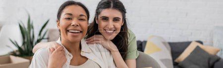 Téléchargez les photos : Joyeuse lesbienne femme étreignant heureuse petite amie multiraciale dans le salon, bannière - en image libre de droit