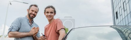 Téléchargez les photos : Heureux père et adolescent fils debout ensemble près de voiture moderne, bannière - en image libre de droit