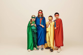 shocked multicultural and preteen kids in colorful superhero costumes with cloaks and masks looking at camera on grey background in studio, International children's day concept  tote bag #655802300
