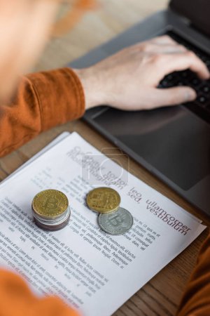 Photo for KYIV, UKRAINE - OCTOBER 18, 2022: golden and silver bitcoins on paper documents near cropped businessman working on laptop at workplace in modern office - Royalty Free Image