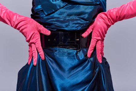 Cropped view of fashionable young woman in cocktail dress and pink gloves touching hips while posing isolated on grey, modern generation z fashion concept, details, close up 