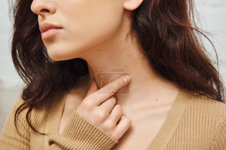 Ausgeschnittene Ansicht einer jungen brünetten Frau bei der Selbstmassage der Schilddrüse am Hals und der Lymphzirkulation zu Hause, Selbstpflegungsritual und ganzheitliches Wellness-Praxiskonzept, Spannungsabbau