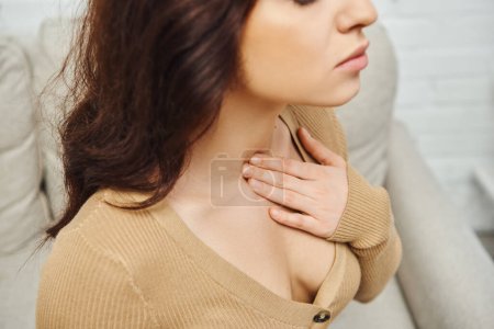 High angle view of young brunette woman in casual jumper massaging neck during lymphatic system self-massage at home, self-care ritual and holistic wellness practices concept, tension relief