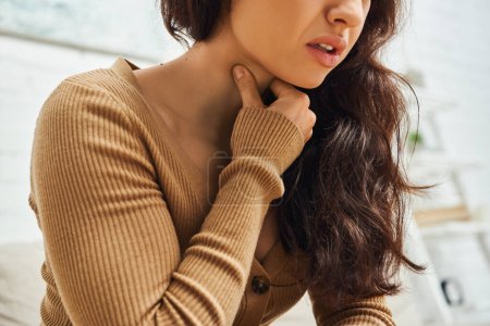 Ausgeschnittene Ansicht einer jungen brünetten Frau im braunen Pullover, die während der Selbstmassage zu Hause unter Nackenschmerzen leidet, Selbsthilferitual und ganzheitliches Heilkonzept, ausgleichende Energie, Spannungsabbau