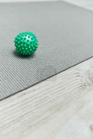 Photo for Close up view of handle massage ball lying on fitness mat on floor at home, natural health practices and home-based massage concept, health and relaxation, beauty and wellness routine - Royalty Free Image