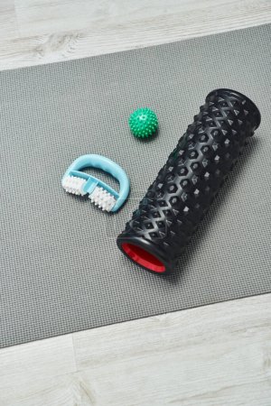 Top view of handle and roller massagers near handle ball lying on fitness mat on floor at home, natural health practices and home-based massage concept, health and relaxation, beauty routine 