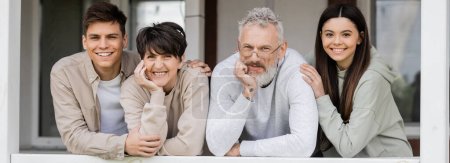 parents day, middle aged parents smiling next to teenage daughter and young adult son on porch of summer house, family celebration, bonding, modern parenting, moments to remember, banner 