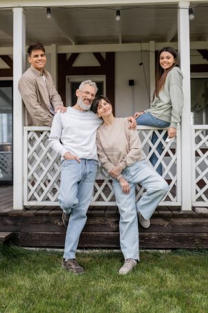 family photo, parents day, middle aged parents posing next to daughter and young adult son on porch of summer house, family celebration, bonding, moments to remember, modern parenting 