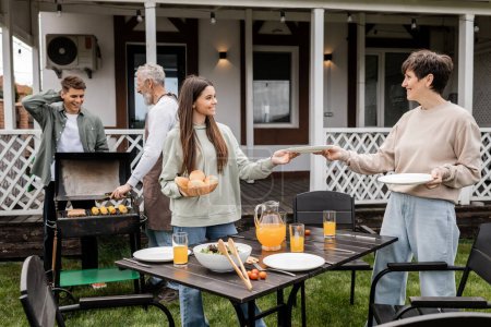 Photo for Parents day, happy teenage girl helping mother serving the table, father and son making bbq, grilling corn, backyard of summer house, suburban life, family bbq party, celebration - Royalty Free Image