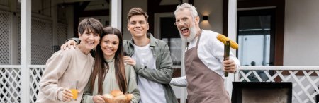 family photo, happy parents day, cheerful middle aged parents having bbq party with teenage daughter and young adult son, excited father holding tongs with grilled corn, looking at camera, banner