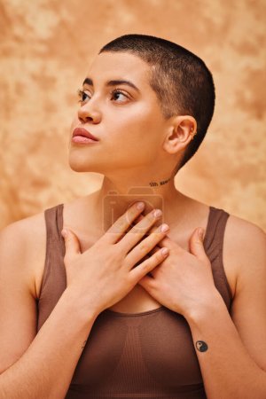 Photo for Body positivity, dreams, curvy and tattooed woman in crop top looking away on mottled beige background, thinking, body love, self-acceptance, generation z, hands near neck, short haired - Royalty Free Image