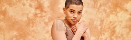 Photo for Body positivity, sensual and tattooed woman in crop top posing on mottled beige background, looking at camera, representation of body, different body shapes, generation z, youth, banner - Royalty Free Image