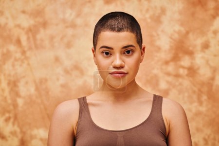 natural look, self-acceptance, young woman with short hair posing on mottled beige background, individuality, looking at camera, generation z, beauty and confidence, body positivity, tattooed 