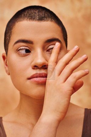 natural look, self-acceptance, young woman with short hair posing on mottled beige background, hand near face, individuality, modern generation z, beauty and confidence, body positivity  