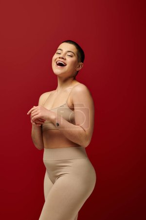 Photo for Self acceptance, amazed and tattooed woman in beige underwear posing on red background, body positivity, curvy fashion, comfortable in skin, curvy model, generation z, self love, short hair - Royalty Free Image