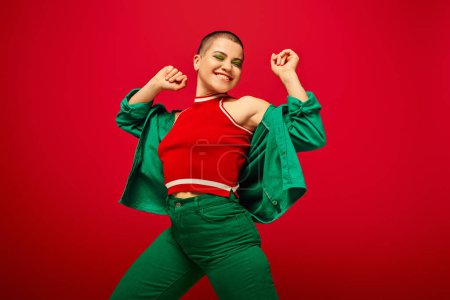 youth culture, stylish appearance, bold makeup, happy and tattooed, short haired woman in green outfit dancing on red background, generation z, youth, vibrant backdrop, individuality, personal style 