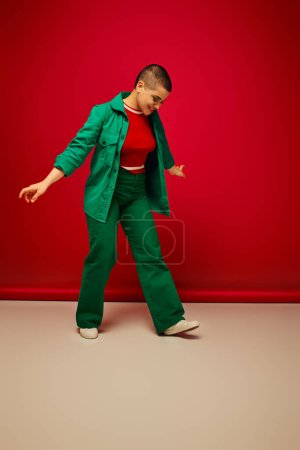 fashion forward, vibrant backdrop, positive and young woman in stylish attire posing on red background, full length, generation z, youth culture, personal style, curvy fashion 