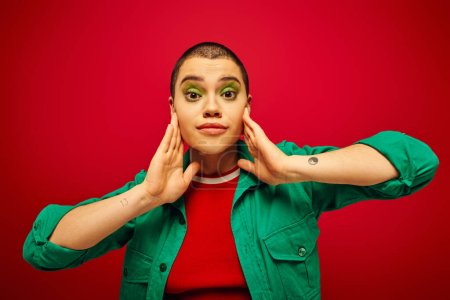 fashion statement, bold makeup, generation z, youth culture, young woman with short hair posing on red background, casual wear, youth culture, vibrant background, stylish appearance 
