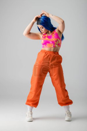 fashion trends, tattooed young woman with blue hair posing in colorful clothes on grey background, full length, casual attire, individualism, modern style, urban fashion, vibrant color, model 
