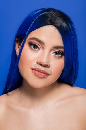 Gesichtspflege, hübsche junge Frau mit gefärbten Haaren posiert auf blauem Hintergrund, Haarfarbe, Individualismus, weibliches Model mit Make-up und trendiger Frisur, lebendige Jugend, Hautperfektion 