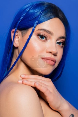 perfección de la piel, mujer joven con el pelo teñido posando sobre fondo azul, color de pelo, individualismo, modelo femenino con maquillaje y peinado de moda, juventud vibrante, tendencias de belleza 