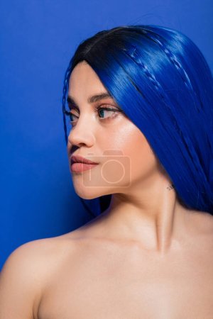 Téléchargez les photos : Concept de jeunesse dynamique, jeune femme tatouée avec des cheveux teints posant sur fond bleu, couleur de cheveux, individualisme, modèle féminin avec maquillage et coiffure à la mode, jeunesse dynamique - en image libre de droit