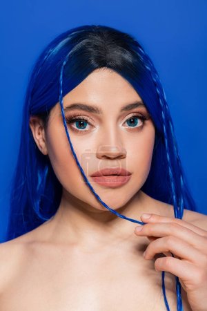 lebendige Jugend, Selbstausdruck, Porträt einer jungen Frau mit gefärbten Haaren, die auf blauem Hintergrund posiert, Haarfarbe, Individualismus, weibliches Modell mit Make-up und trendiger Frisur, Selbstausdruck  