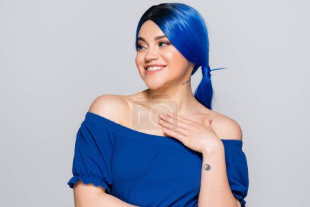Photo for Beauty trends, dyed hair, summer fashion, happy young woman with bare shoulders posing in bright blouse on grey background, blue hair color, hairstyle, female model, makeup and beauty - Royalty Free Image