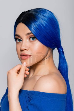 Photo for Beauty trends, dyed hair, portrait of tattooed young woman with bare shoulders posing in bright blouse on grey background, blue eyes and hair color, hairstyle, female model, makeup and beauty - Royalty Free Image