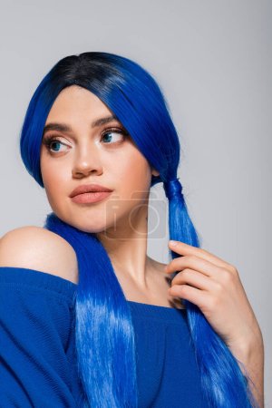 vibrant youth, sensual young woman with blue eyes and hair looking away on grey background, individualism, self expression, beauty trends, modern subculture, makeup and hairstyle