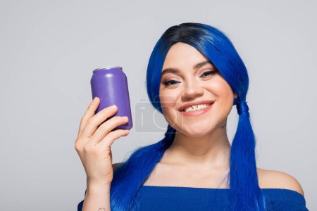 Sommerkonzept, fröhliche junge Frau mit blauen Haaren, die eine Getränkedose auf grauem Hintergrund hält, moderne Subkultur, Individualismus, Jugend und Lifestyle, lebendige Farbe, Selbstausdruck, einzigartige Identität 