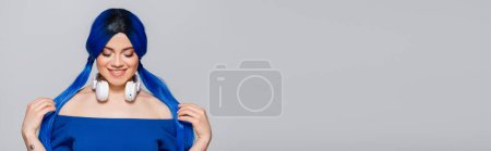 Musikliebhaberin, glückliche junge Frau mit blauen Haaren und kabellosen Kopfhörern, die auf grauem Hintergrund lächelt, lebendige Jugend, Individualismus, moderne Subkultur, Selbstausdruck, Tätowierung, Sound, Banner