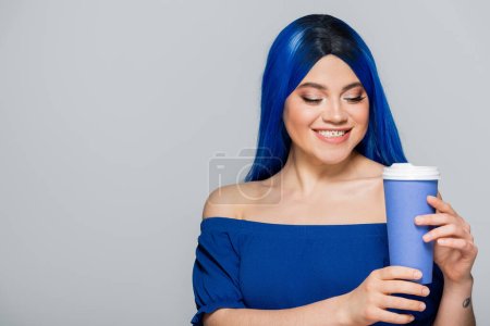 paper cup, happy young woman with blue hair and eyes holding coffee to go on grey background, takeaway, caffeine, energy, tattoo, vibrant color, self expression, individualism 