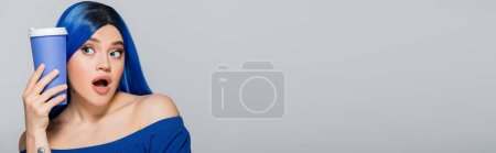 Photo for Disposable cup, shocked young woman with blue hair and eyes holding coffee to go on grey background, takeaway, caffeine, energy, tattoo, vibrant color, self expression, individualism, banner - Royalty Free Image