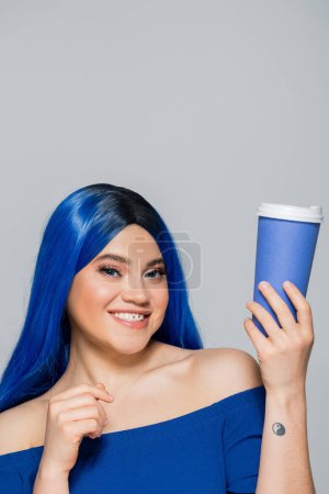 tasse en papier, jeune femme heureuse avec les cheveux bleus et les yeux tenant café pour aller sur fond gris, à emporter, caféine, énergie, tatouage, couleur vibrante, expression de soi, individualisme 