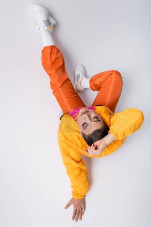 top view, creative photography, fashion statement, tattooed young woman in colorful clothes sitting on grey background, urban style, individualism, vibrant and youthful energy, stylish look 