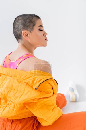 urban fashion, young woman in colorful clothes posing on grey background, closed eyes, urban style, individual style, vibrant and youthful energy, urban fashion, generation z, casual attire 
