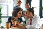 overjoyed african american and multiracial female friends holding coffee to go and laughing with closed eyes near women on blurred background in interest club, solidarity and understanding concept t-shirt #664266550