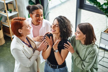 Photo for High angle view of happy motivation coach and multicultural girlfriends embracing happy multiracial woman smiling and gesturing with closed eyes, moral support and mental wellness concept - Royalty Free Image