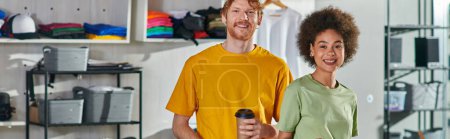 Photo for Smiling young multiethnic craftspeople with coffee to go looking at camera while standing and working on project in blurred print studio at background, start-up innovation concept, banner - Royalty Free Image