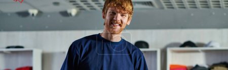 Portrait of young redhead craftsman in casual clothes looking at camera while standing in blurred print studio at background, self-made success concept, banner 