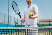 cropped view of man in sportswear holding tennis racquet and ball near net, player, hobby and sport mug #665313182