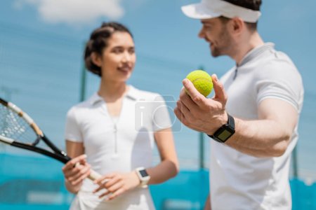 skupienie się na piłce, niewyraźny mężczyzna patrząc na dziewczynę, ucząc jak grać w tenisa na korcie, sport