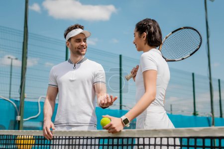szczęśliwy mężczyzna i kobieta rozmawiający na korcie tenisowym, sport letni, para rozrywki, fitness na świeżym powietrzu