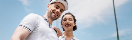 Téléchargez les photos : Bannière, couple joyeux en tenue active regardant la caméra sur le court de tennis, passe-temps et sport - en image libre de droit
