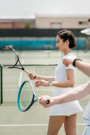 Téléchargez les photos : Femme en jupe de tennis pratiquant sur le court de tennis, tenant raquette, petit ami et petite amie, sport - en image libre de droit